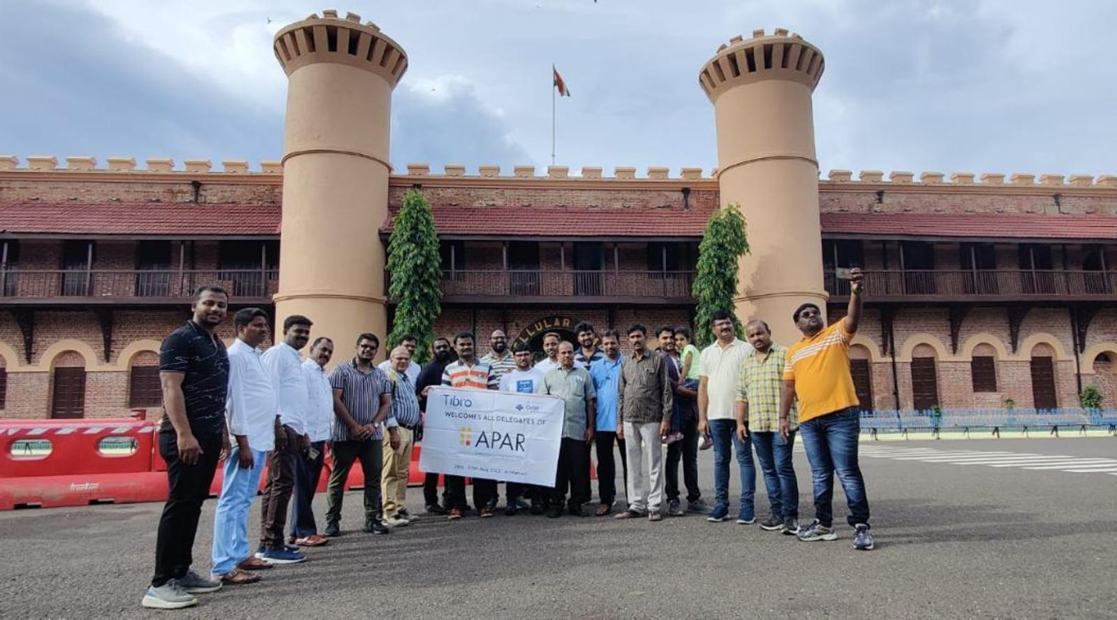 A group poses with a banner in front of a historic castle.