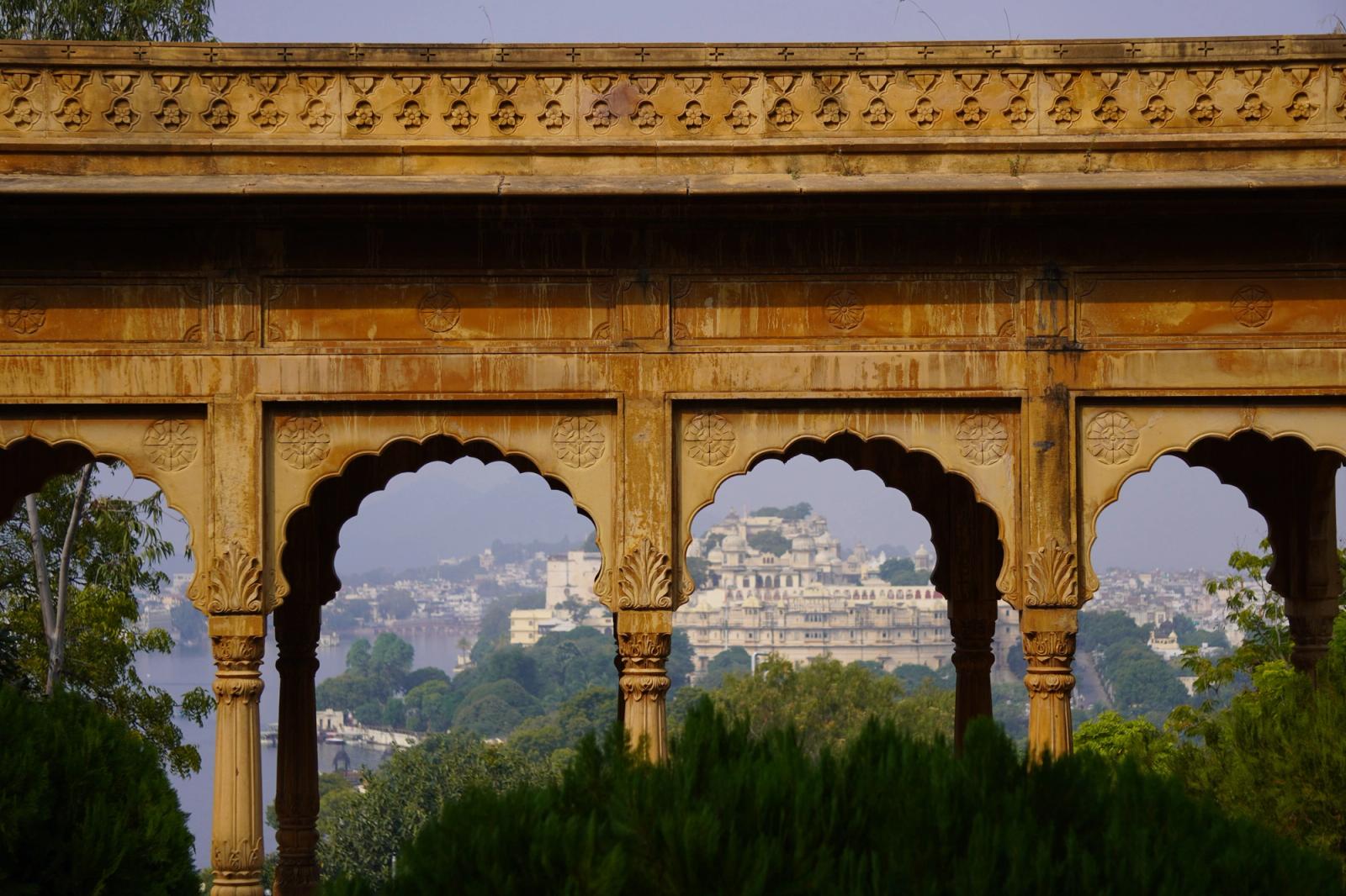 View of Udaipur Palace framed by an ornate historic archway in India