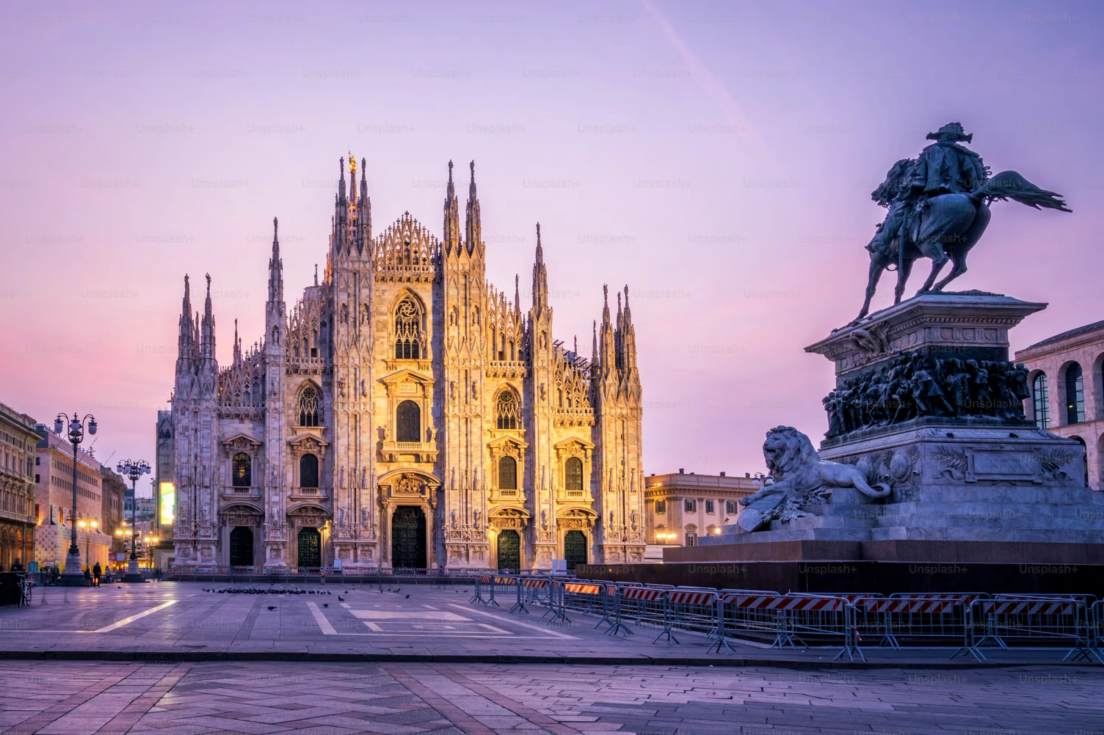 Gothic cathedral with spires beside an equestrian statue at dusk