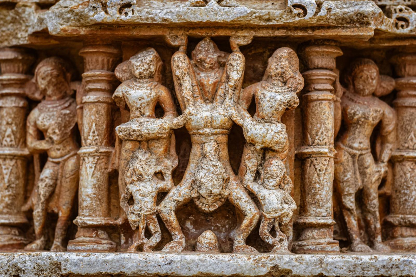 Weathered stone temple carving of dancing figures in relief