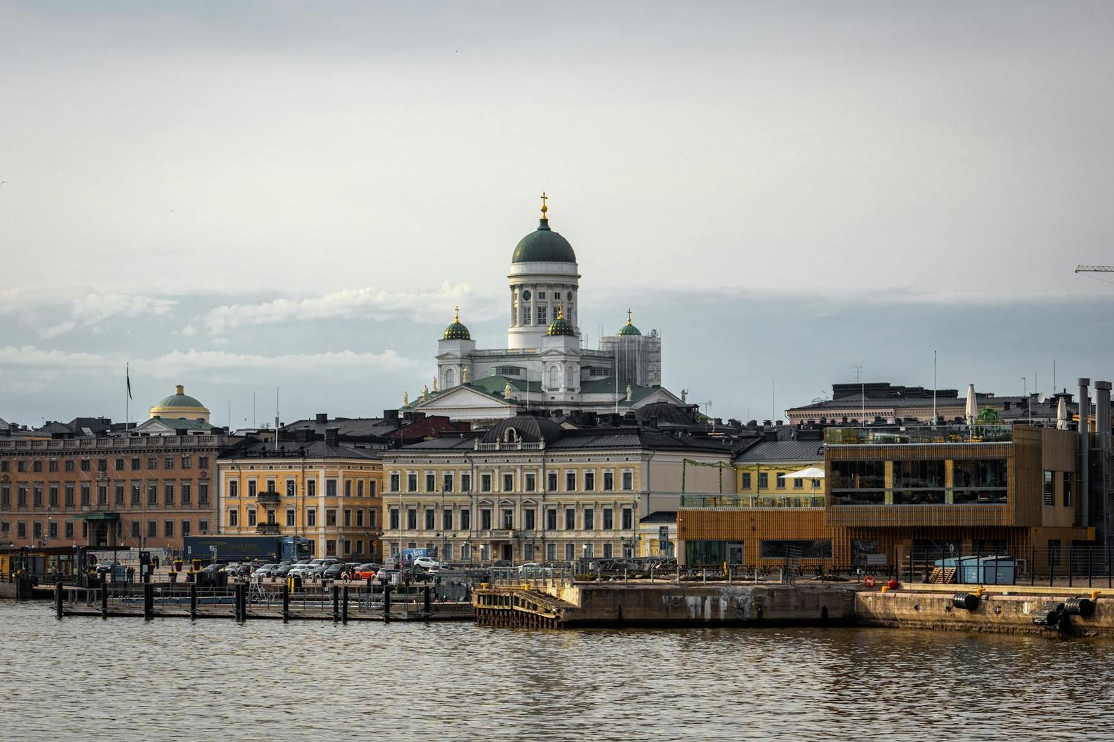 A domed cathedral overlooking a harbourfront row of pastel buildings