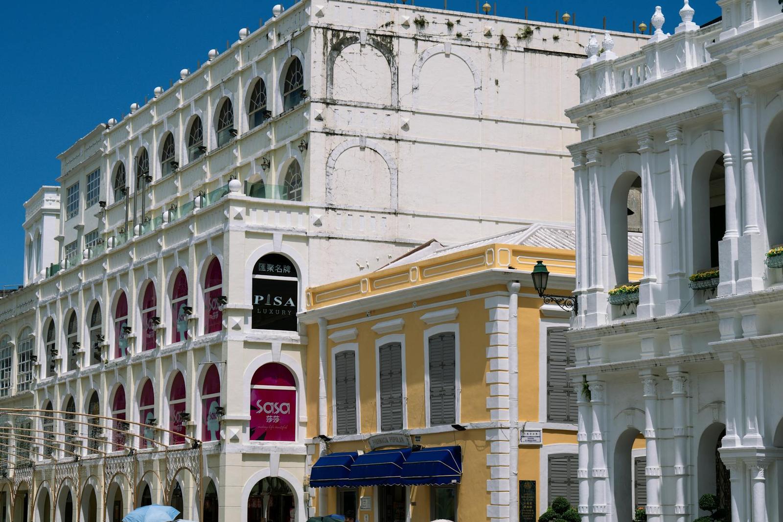 Pastel colonial-style buildings with arched arcades along a sunny street