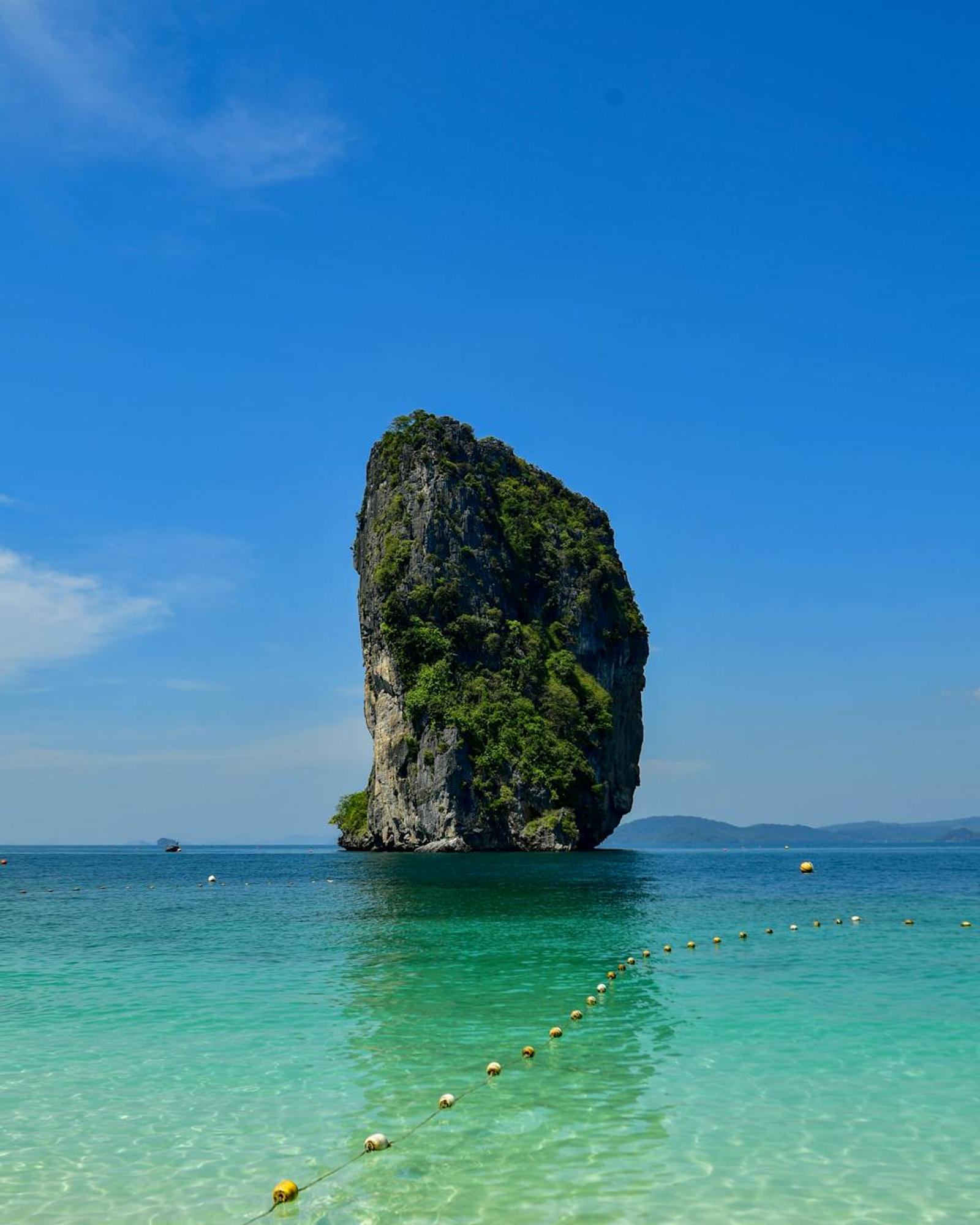 Solitary limestone sea stack rising from clear turquoise shallows