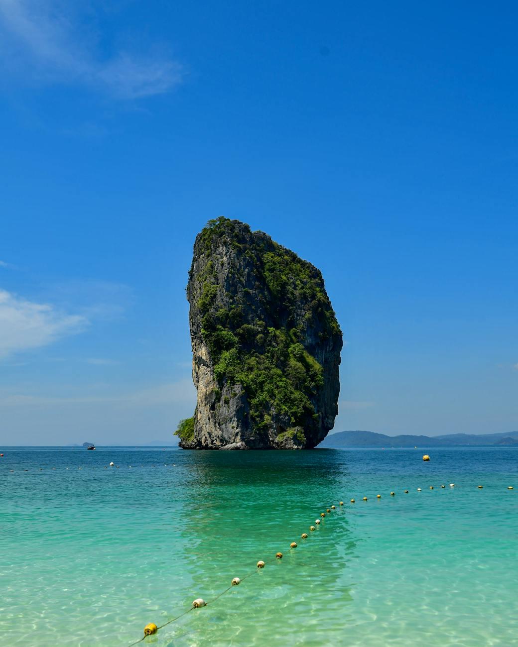 Solitary limestone sea stack rising from clear turquoise shallows