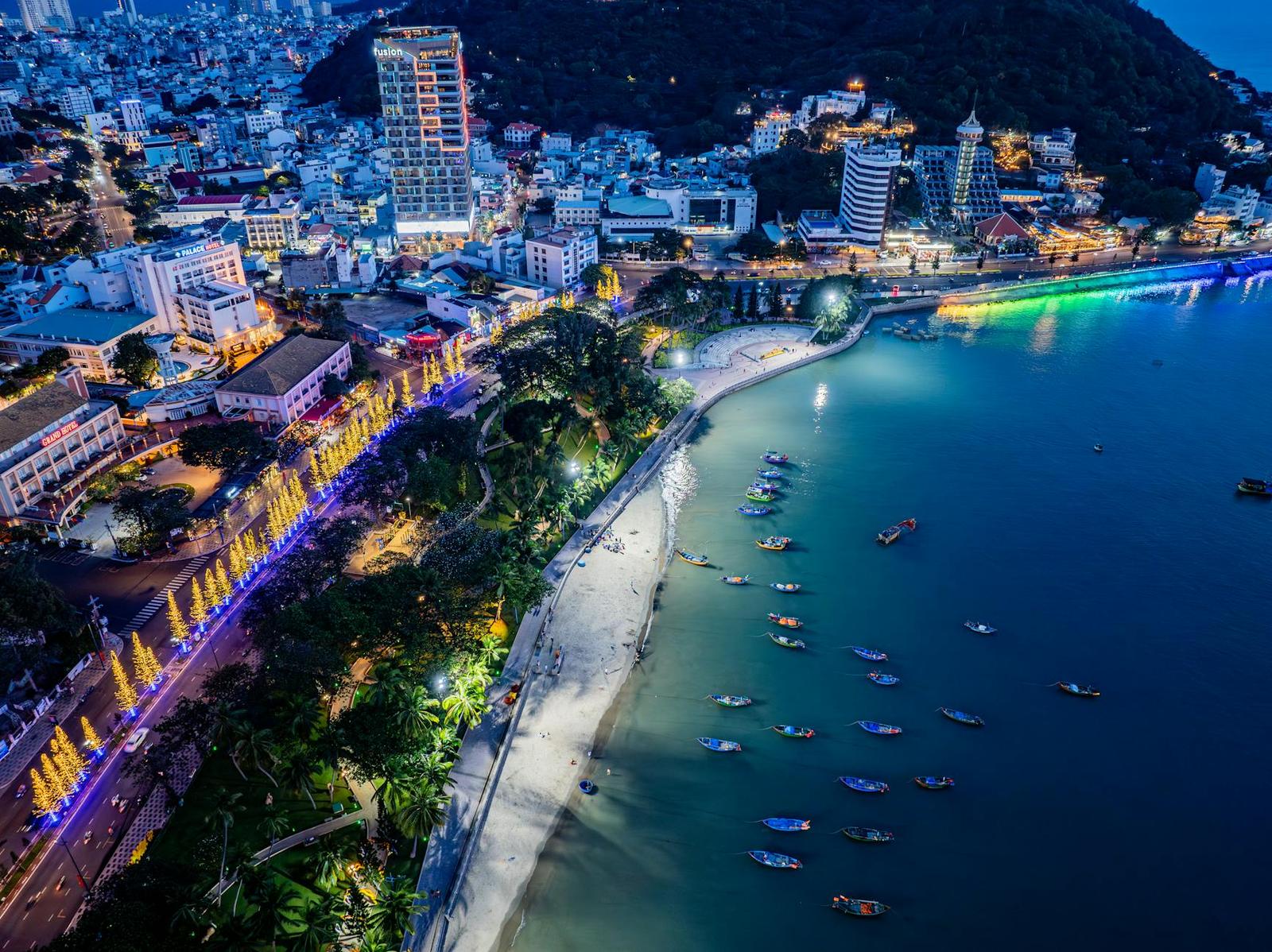 Illuminated coastal city skyline at night curving around a lit waterfront promenade