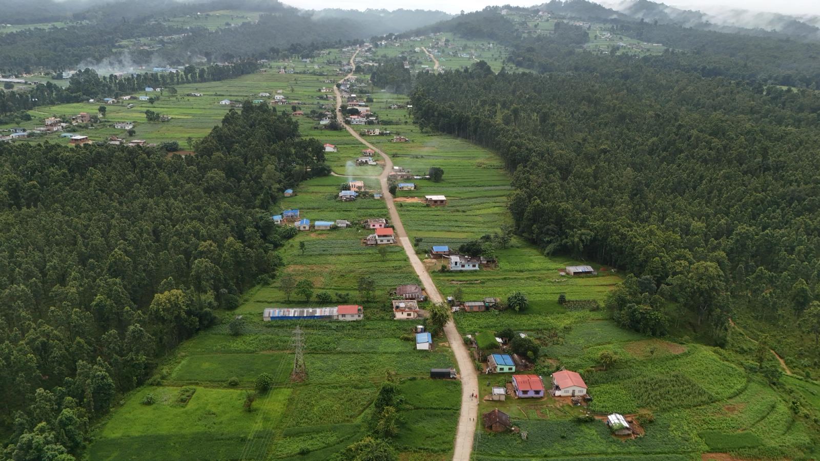 Aerial view of village with lush greenery and dense forest in a mountainous region