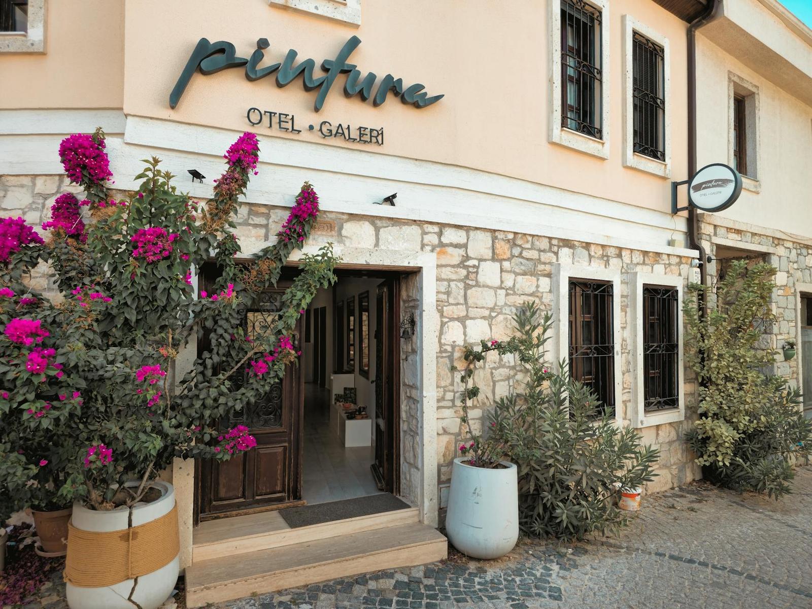 A stone hotel facade with a bougainvillea in bloom by the entrance
