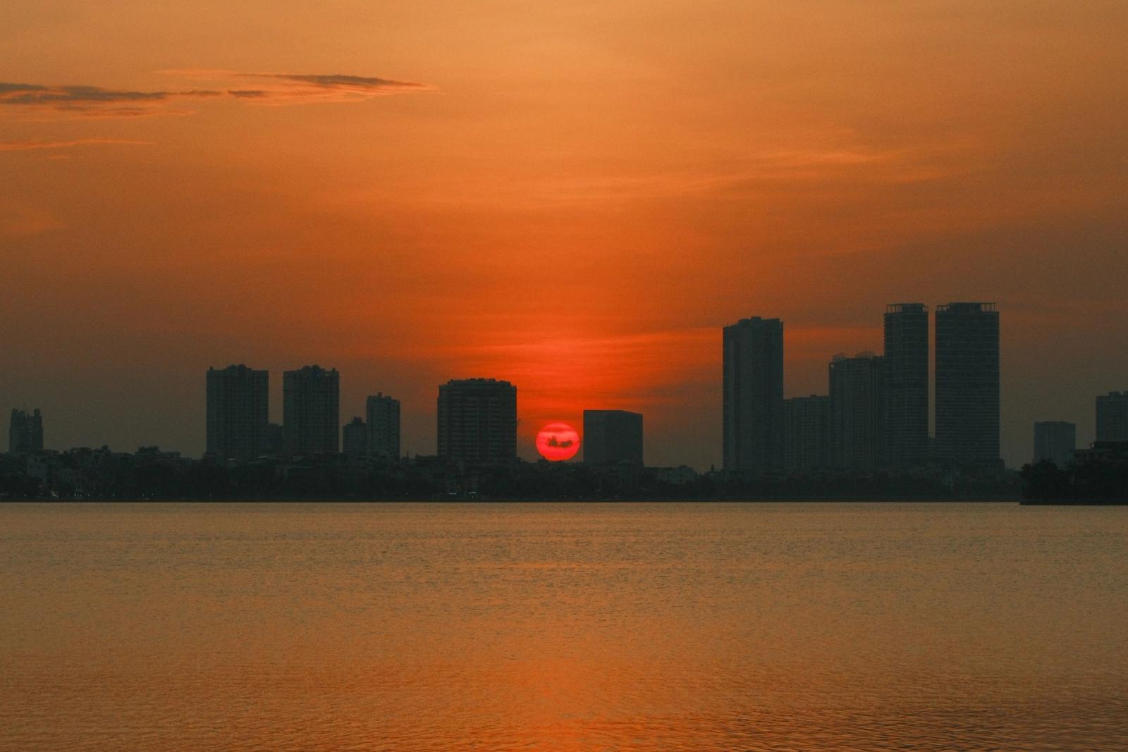Breathtaking sunset over Hanoi's skyline reflecting on tranquil water with vivid orange hues