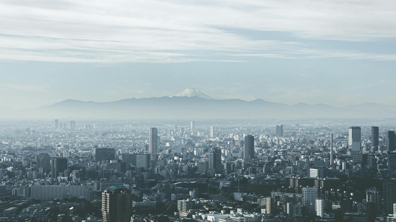 A hazy city skyline with a snow-capped volcano rising in the distance