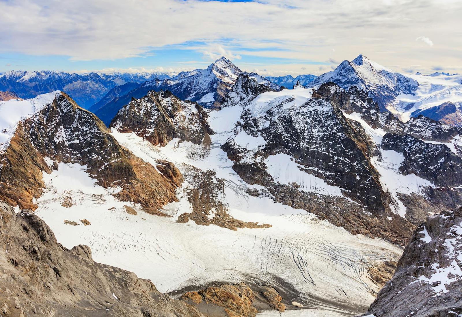 Aerial view of a crevassed glacier winding between rocky summits