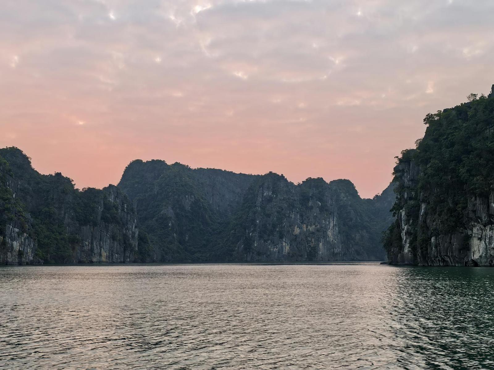 Beautiful view of Halong Bay's limestone formations with a pink sunset sky