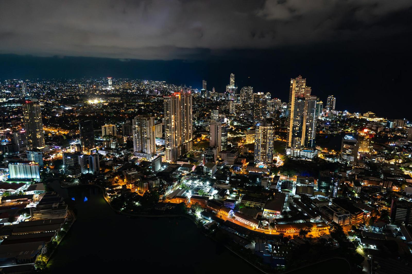 Aerial night view of a dense coastal city skyline lit up in gold and white