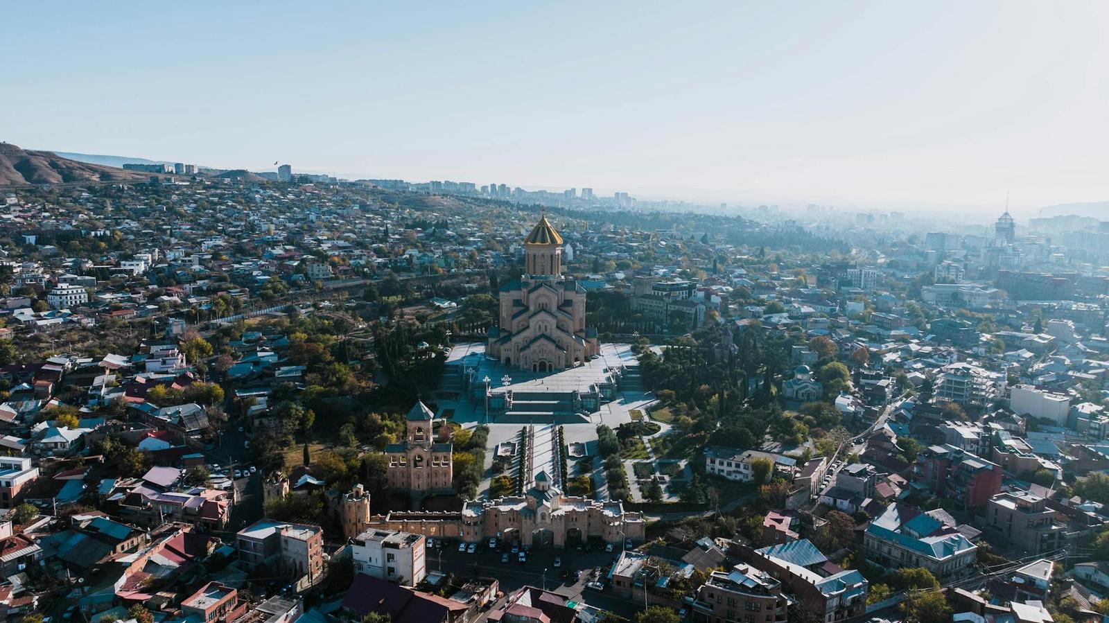 Aerial view of a golden-domed cathedral surrounded by a hillside city