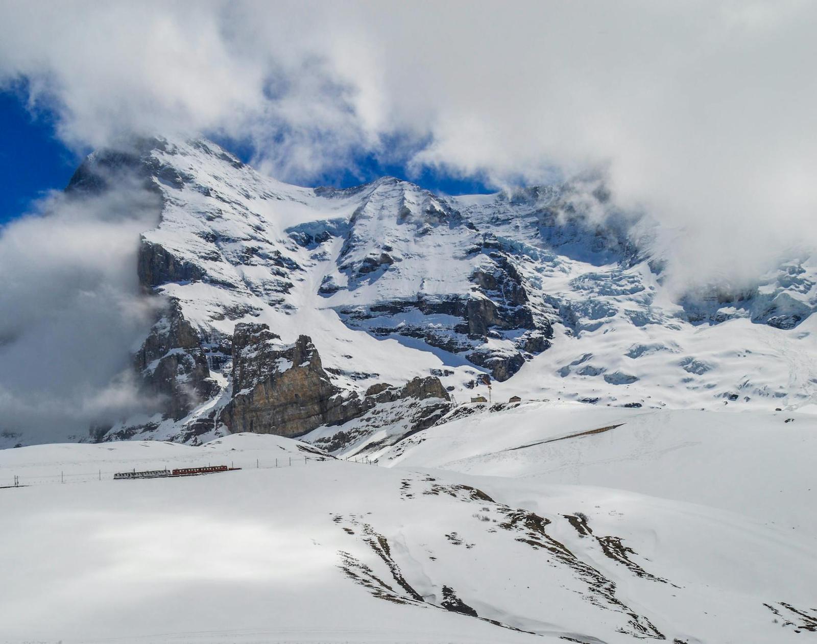Cloud-wrapped snowy peak above a mountain railway platform