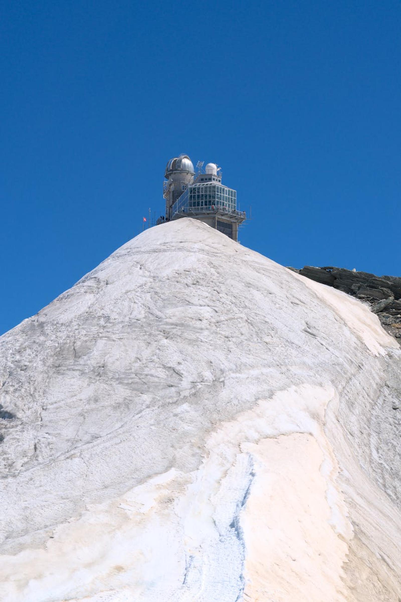Explore the iconic Jungfraujoch Observatory atop snowy peaks under clear blue skies