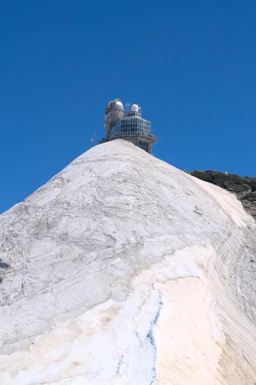 Explore the iconic Jungfraujoch Observatory atop snowy peaks under clear blue skies