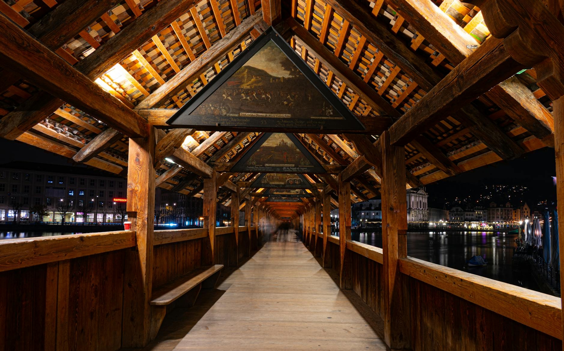 Inside a covered wooden bridge lined with painted historical panels along its beams