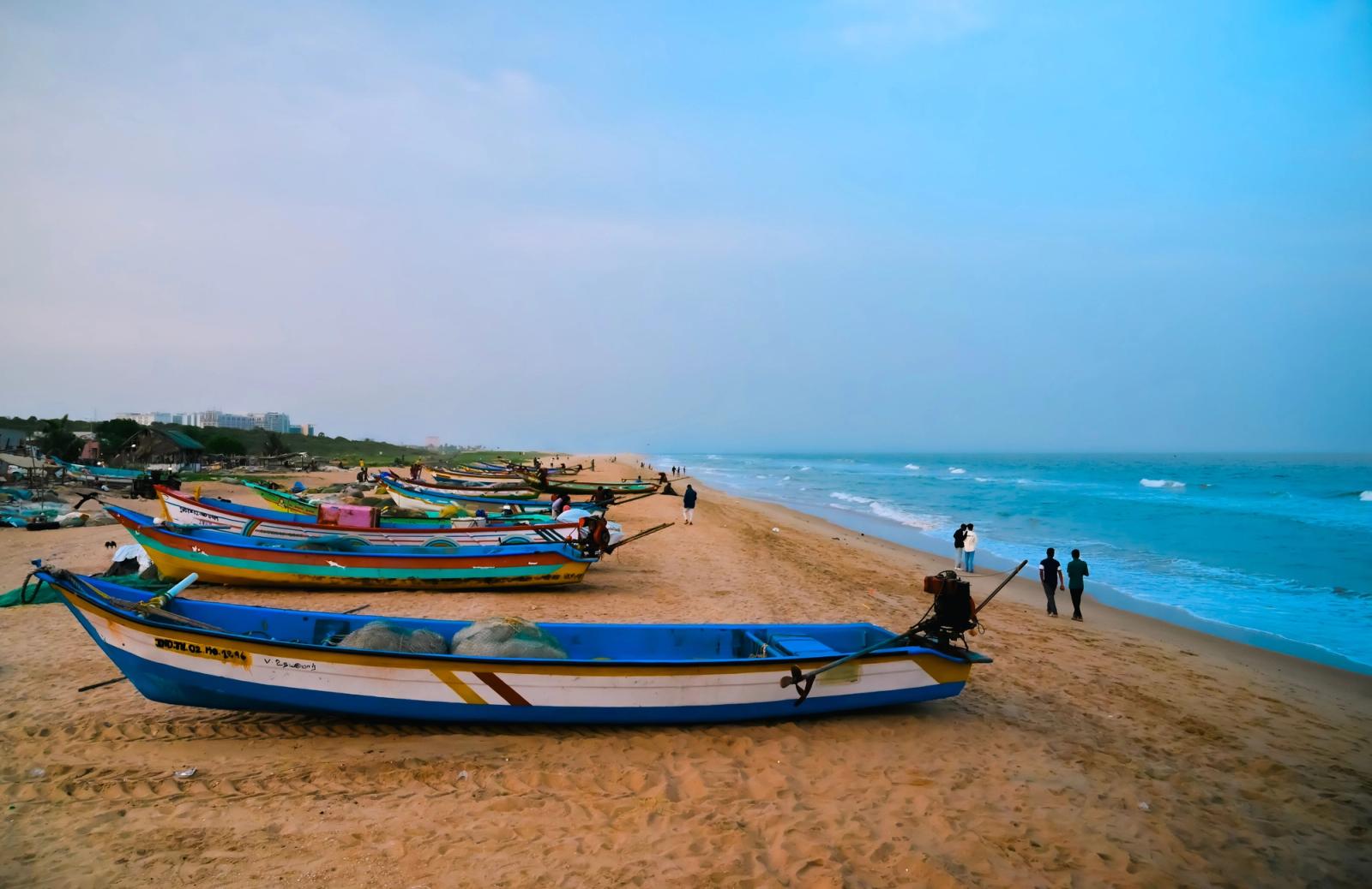 Colorful fishing boats on the sandy beach at sunrise in Chennai, India