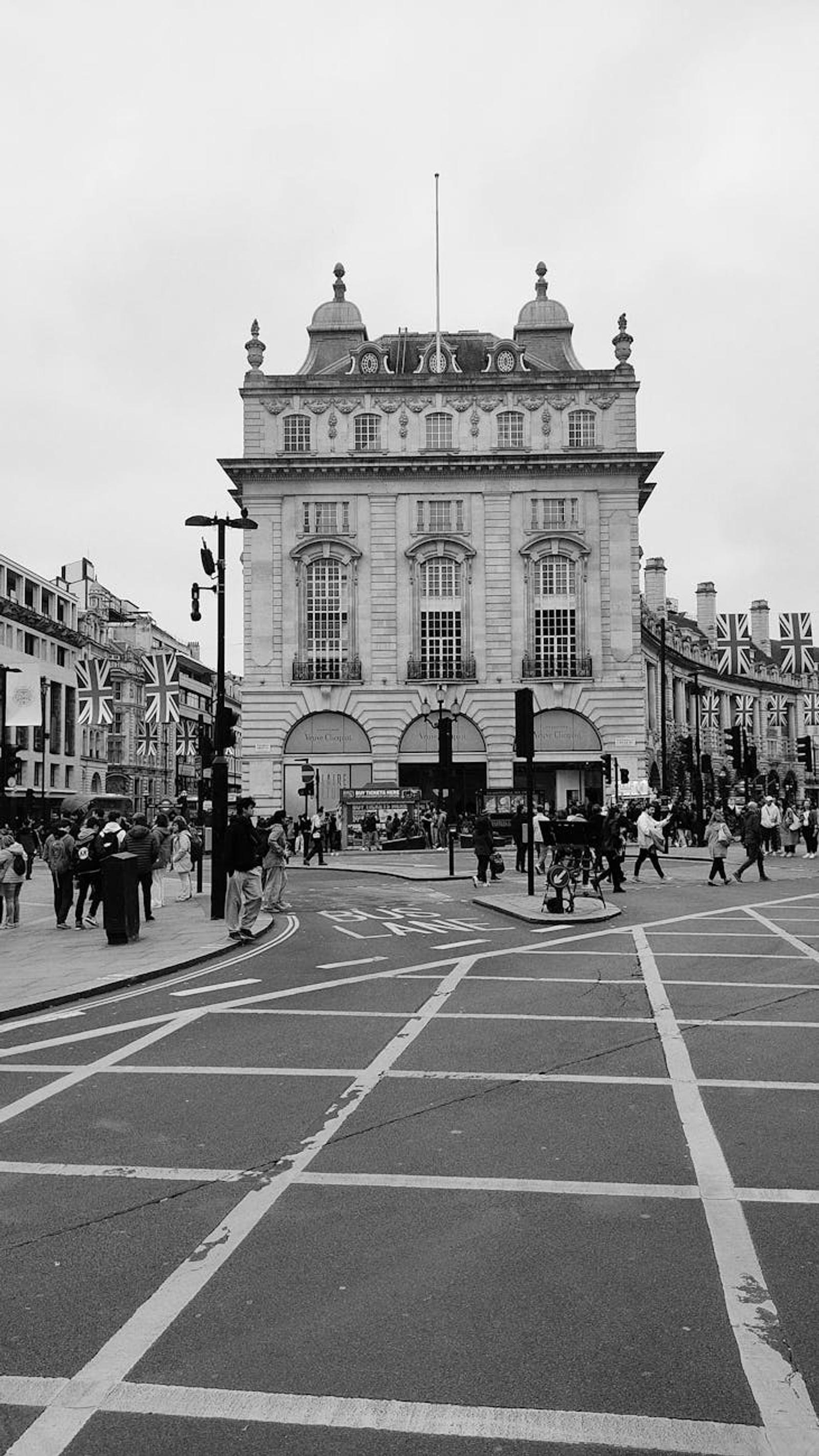 Black-and-white view of pedestrians crossing a busy city plaza