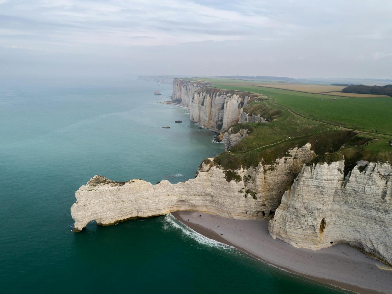 Aerial view of chalk cliffs and a natural arch along a coastline