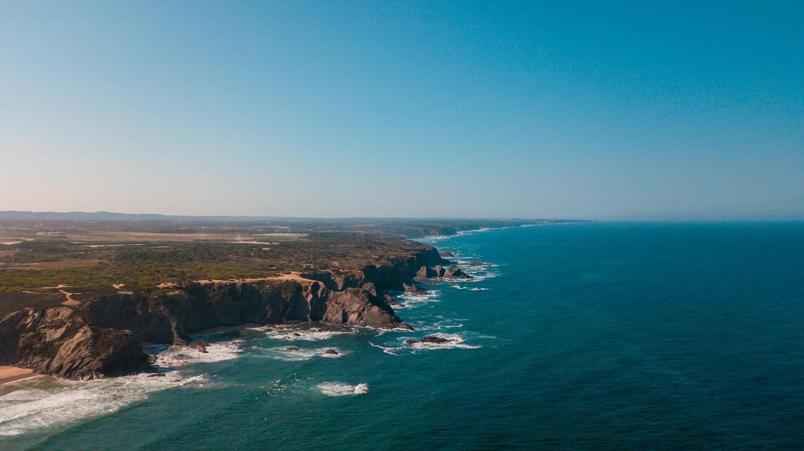 Aerial view of rugged cliffs along a coastline meeting the sea