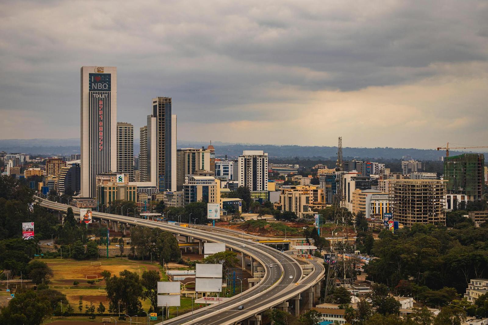 An elevated highway curving through a city skyline under cloudy skies