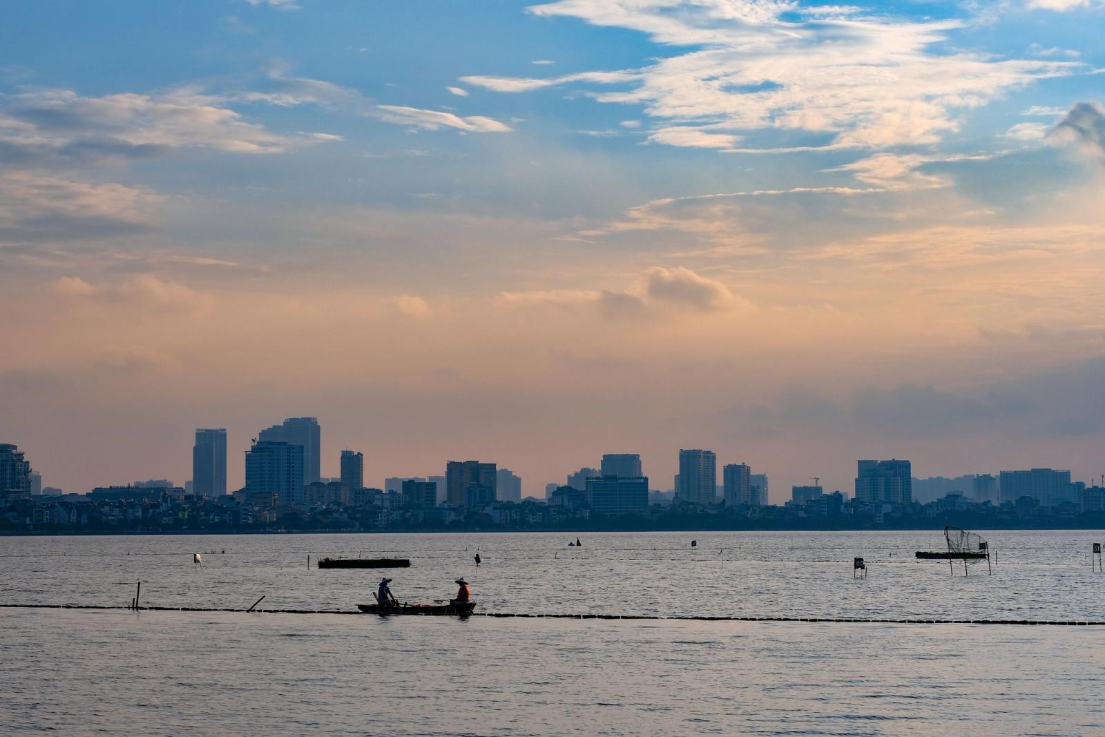 Serene sunset view over West Lake with Hanoi skyline, capturing a tranquil urban scene