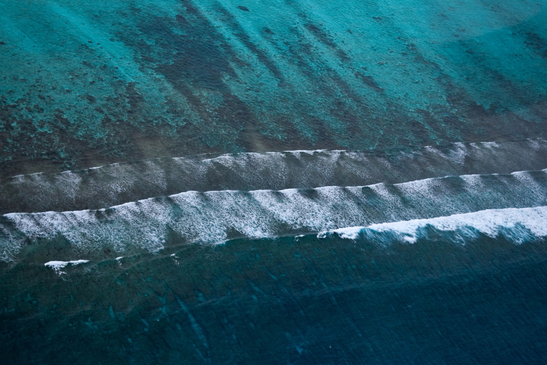 Breathtaking aerial view of turquoise waters and waves crashing on the shores of the Maldives