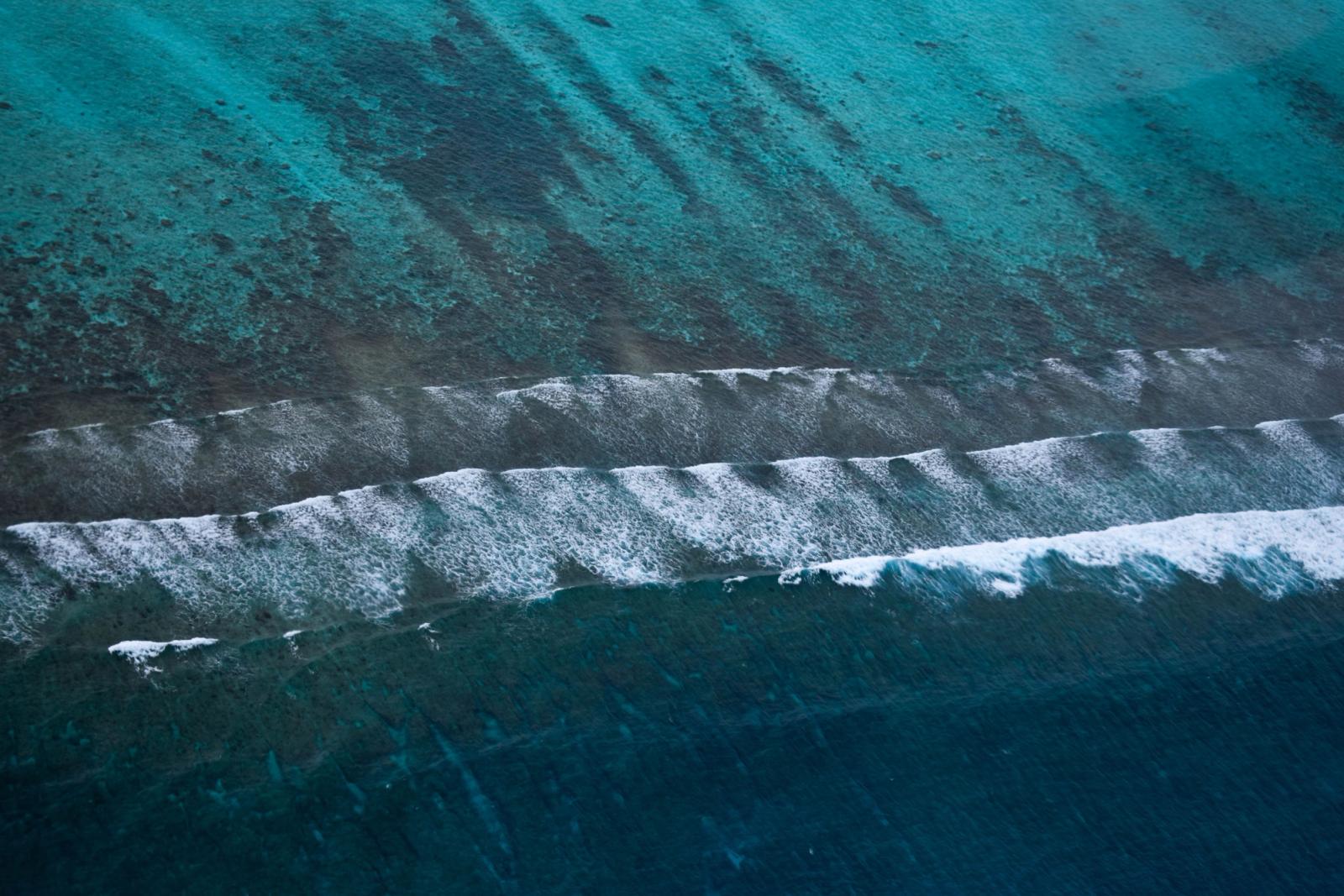 Breathtaking aerial view of turquoise waters and waves crashing on the shores of the Maldives