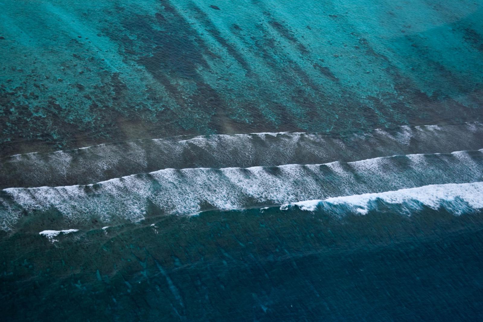 Breathtaking aerial view of turquoise waters and waves crashing on the shores of the Maldives