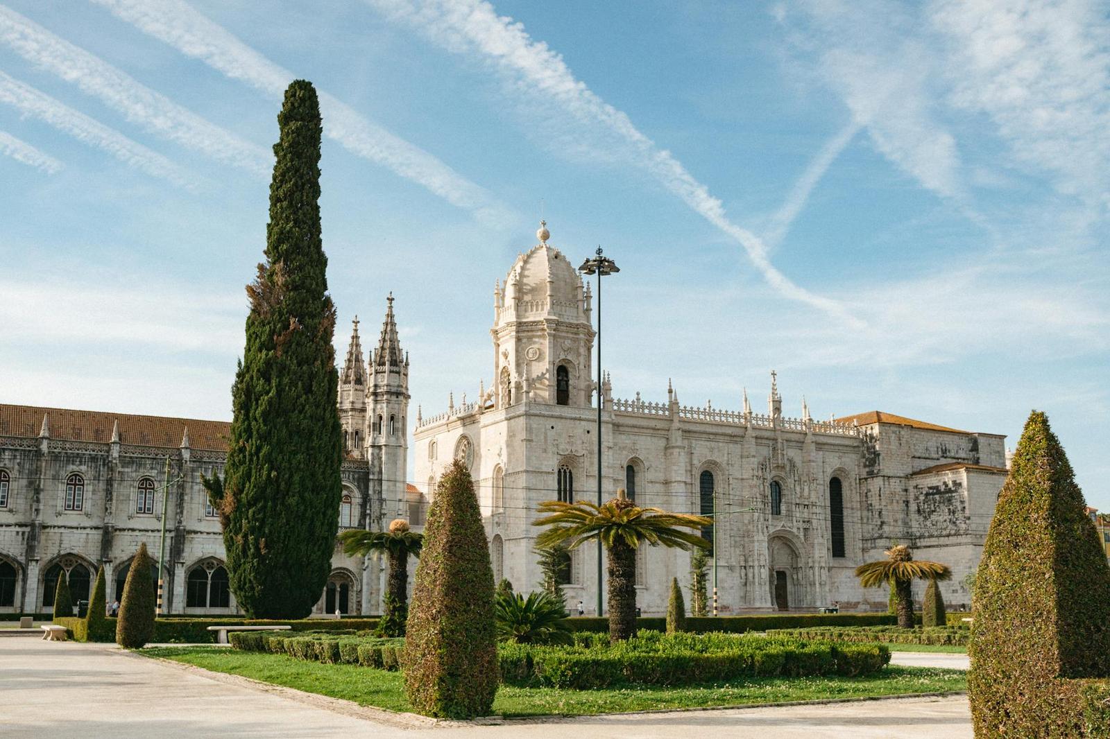 Stunning view of Jerónimos Monastery's gothic architecture amidst lush gardens in Lisbon, Portugal