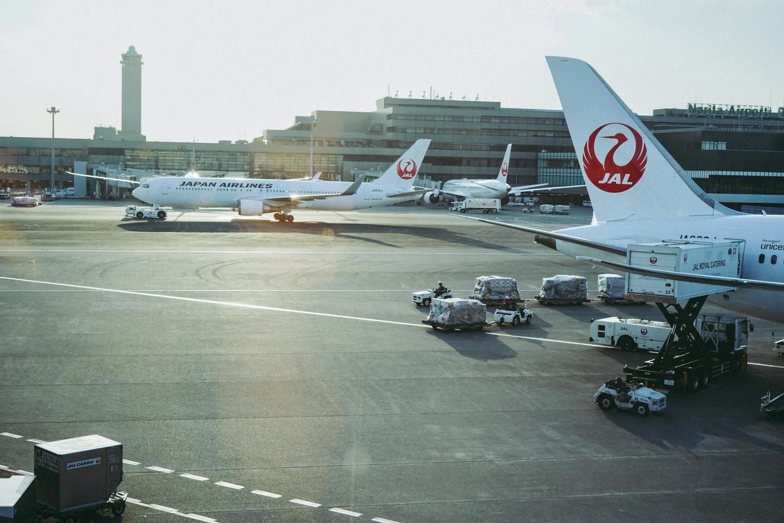 Airliners parked at an airport gate with ground crew and equipment nearby