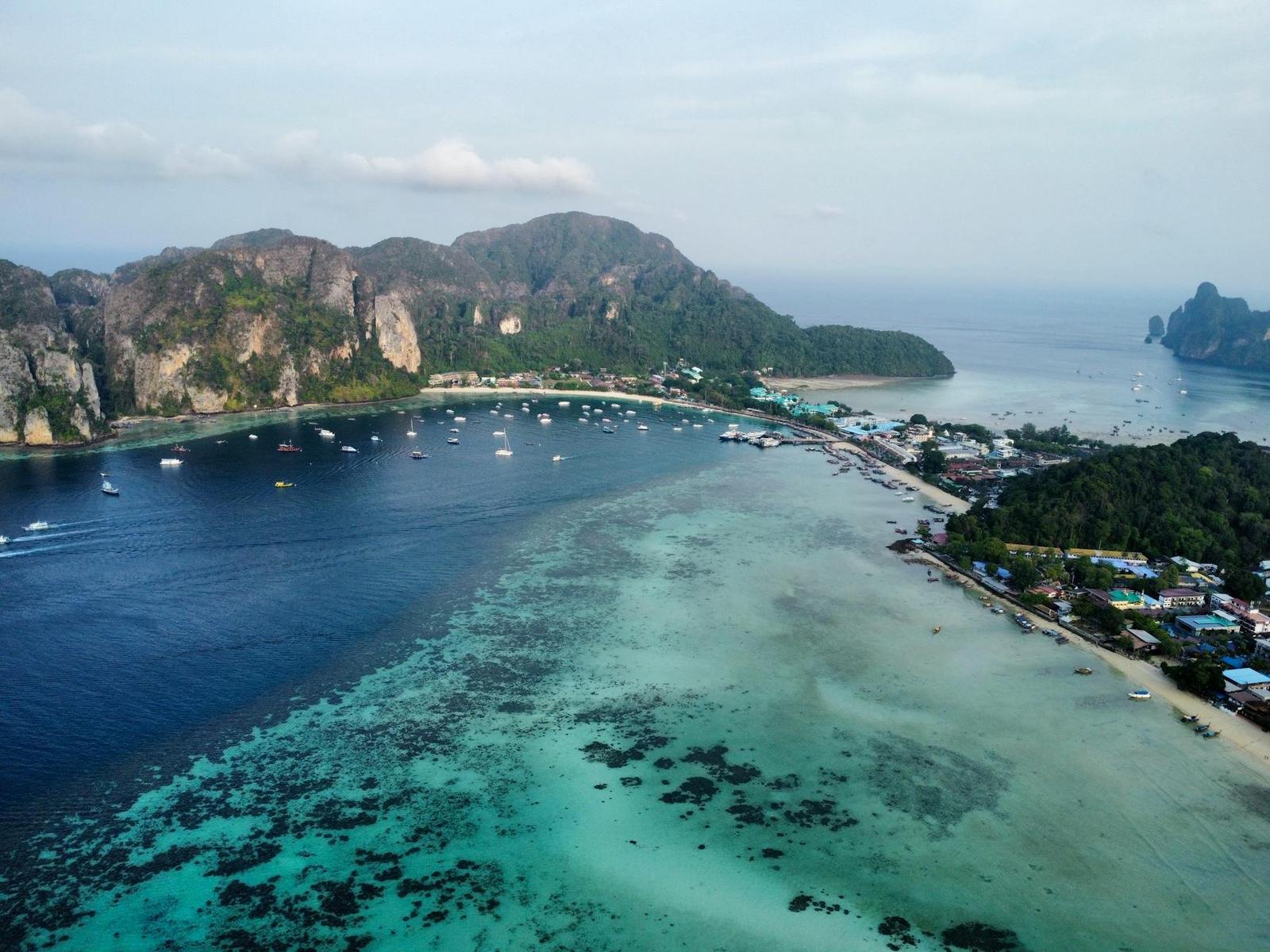 Aerial view of a turquoise reef bay with boats anchored beside limestone islands