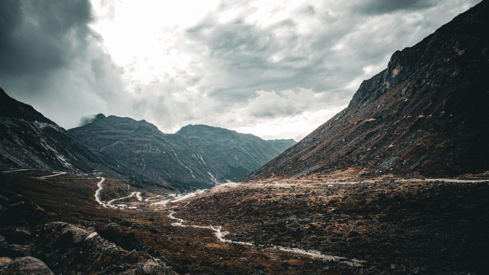 A stunning mountain pass under a dramatic cloudy sky, perfect for travel and adventure themes