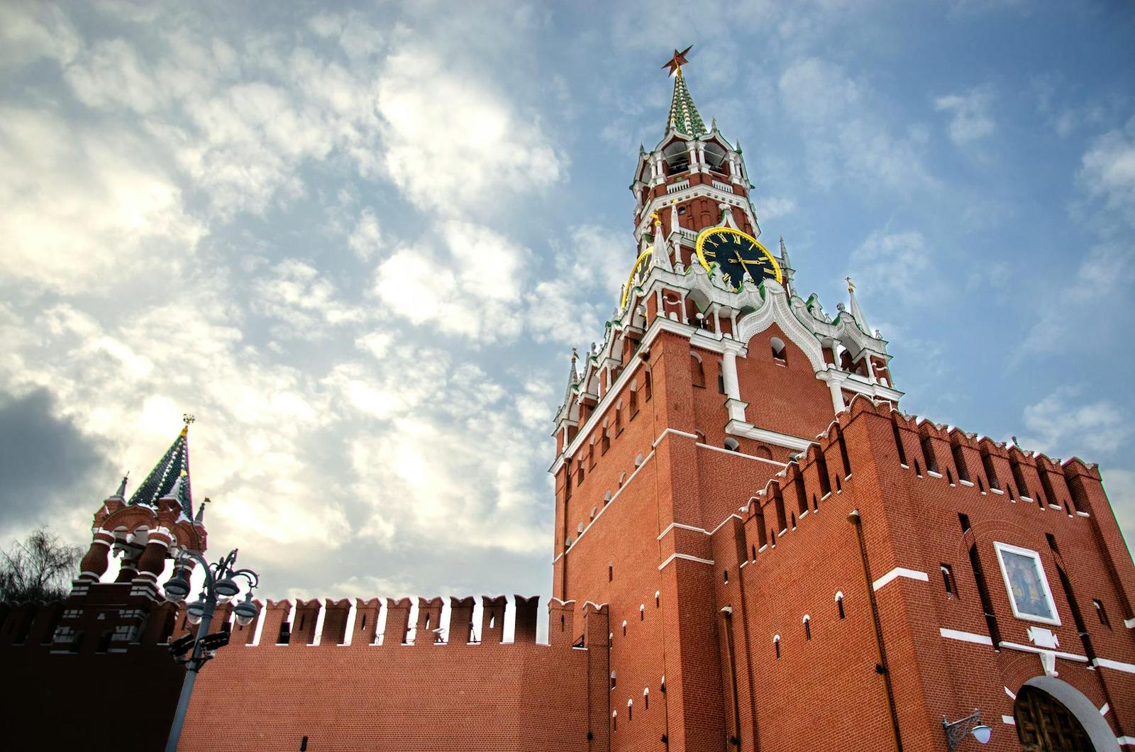 A red brick clock tower with a star spire beside a fortress wall
