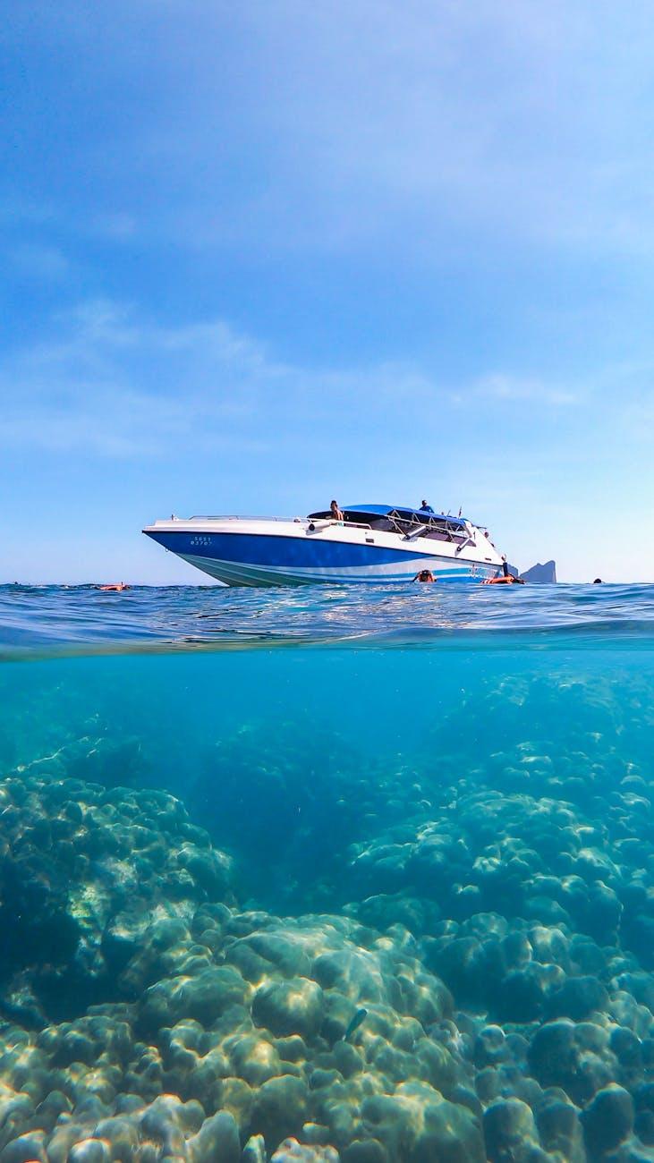 Speedboat anchored above a coral reef with swimmers in clear water