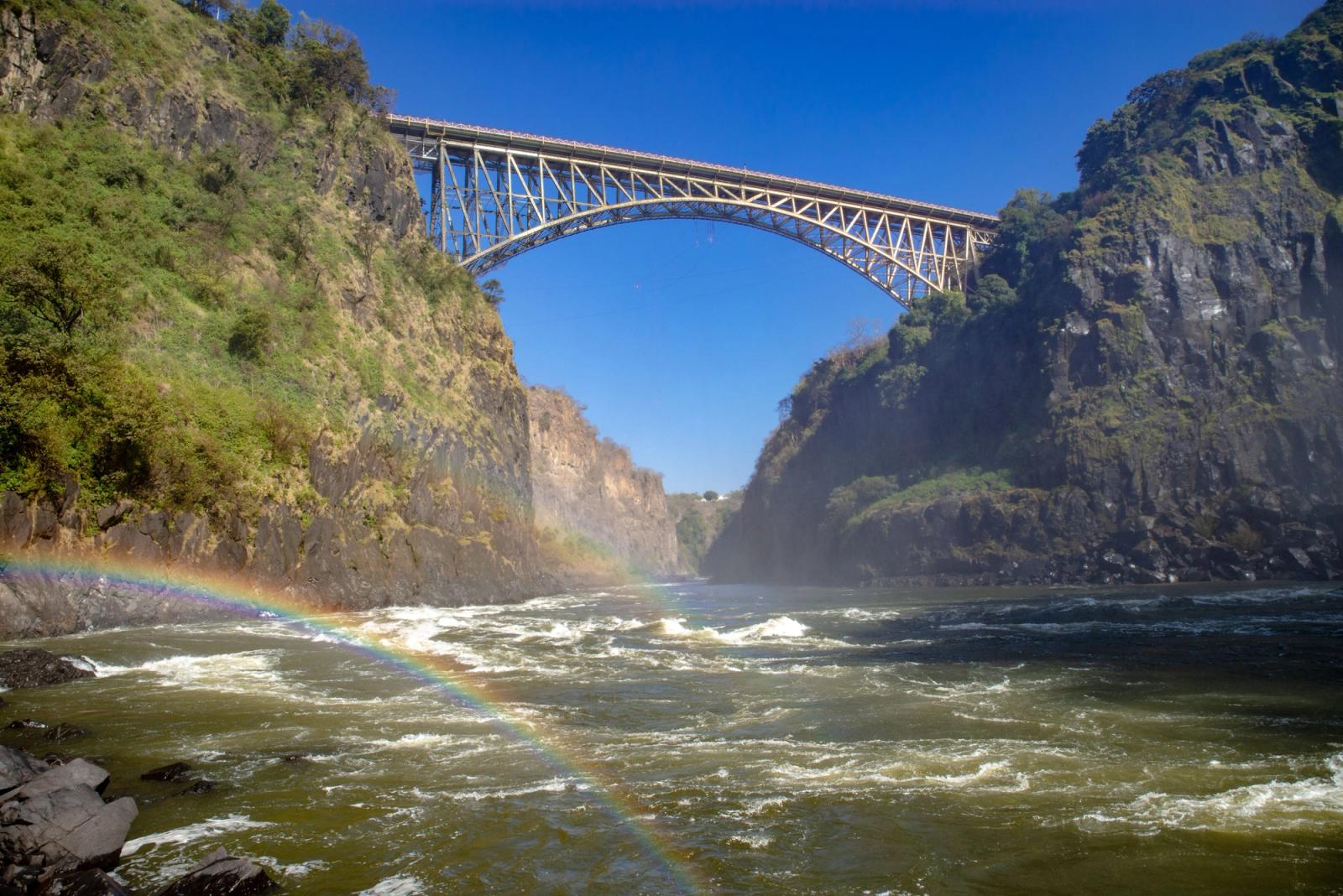 Stunning view of Victoria Falls Bridge surrounded by cliffs and a vibrant rainbow