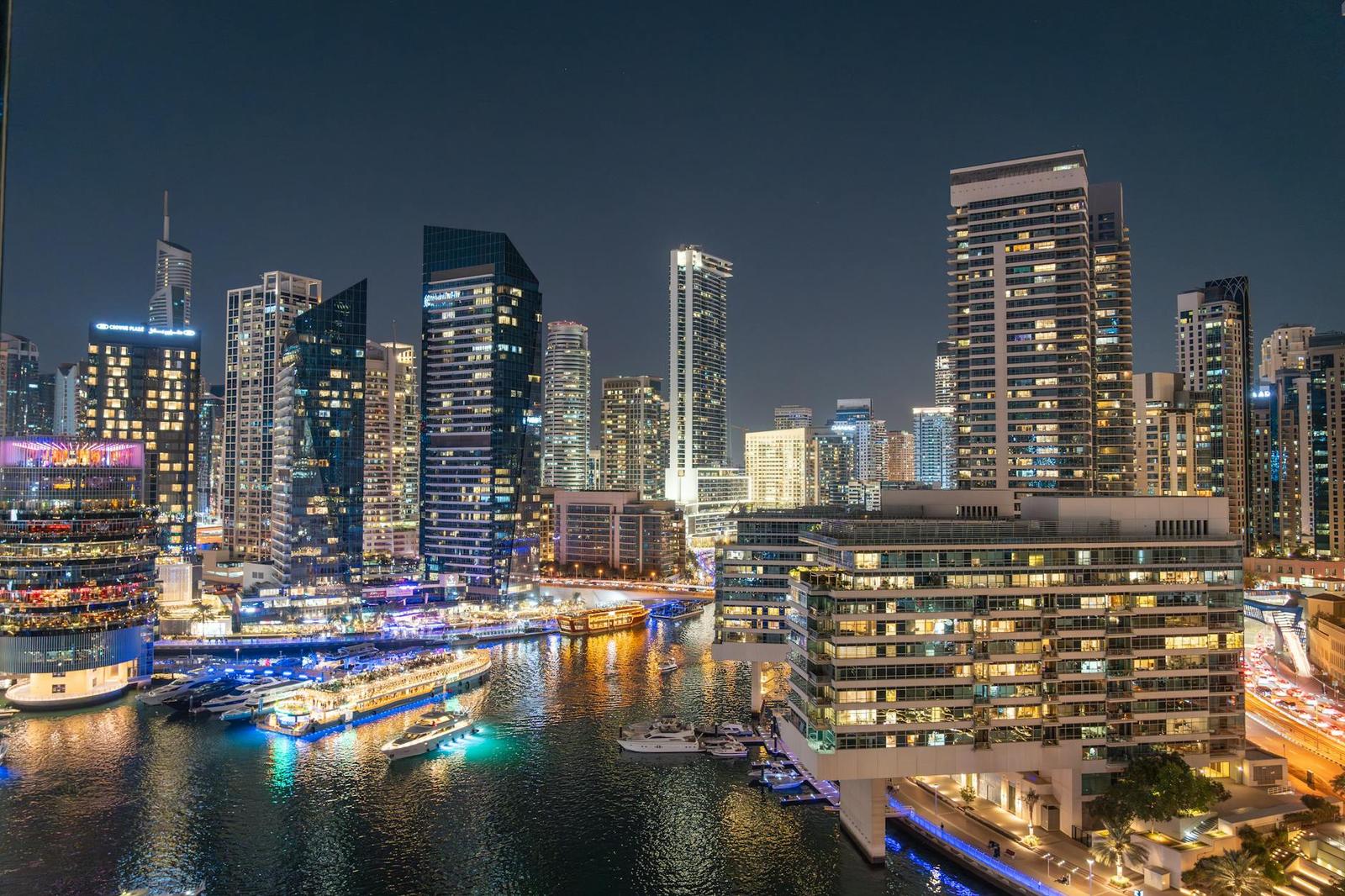 A marina skyline lit up at night with boats moored along the water