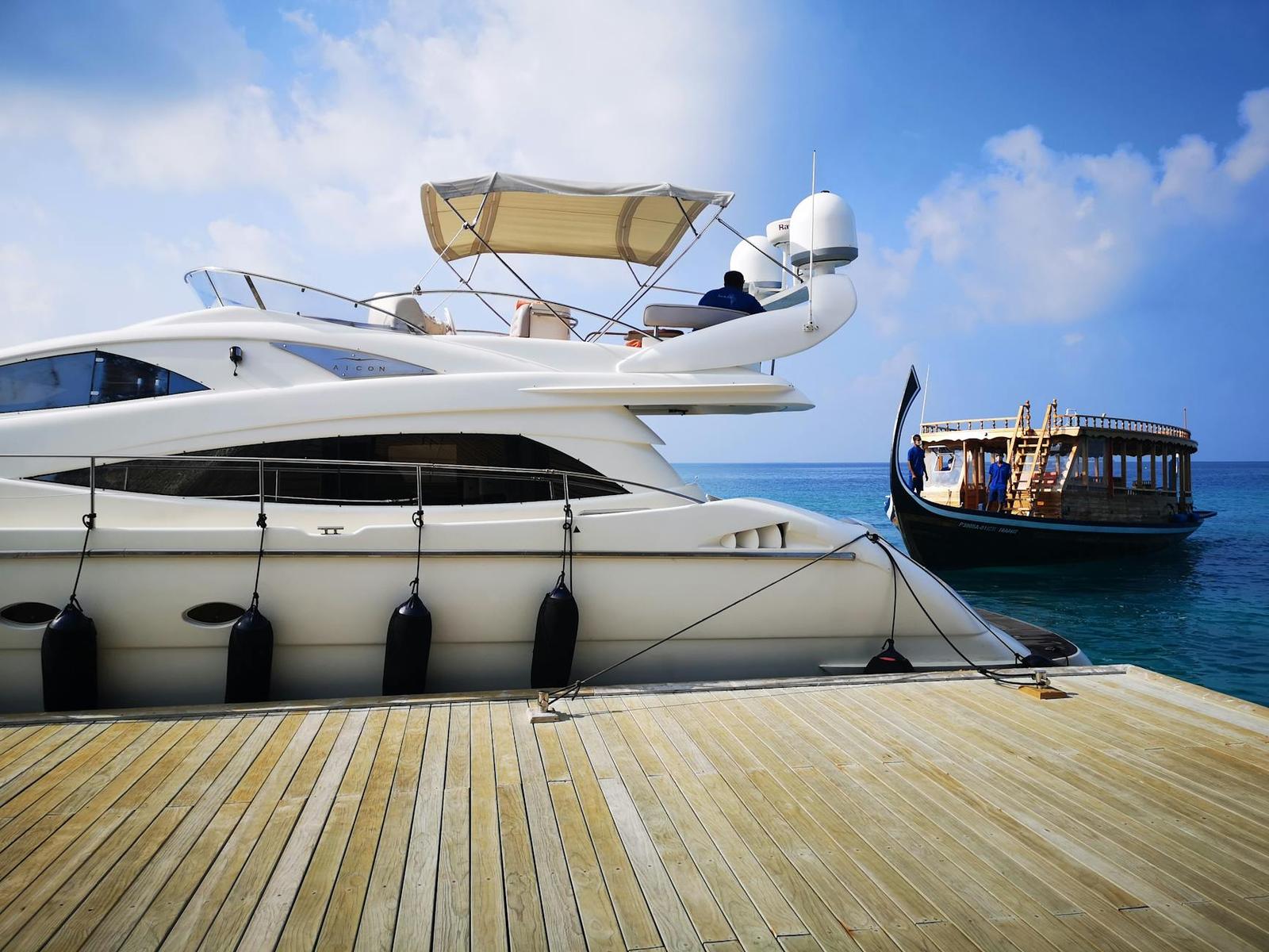 A moored yacht beside a traditional wooden dhoni boat
