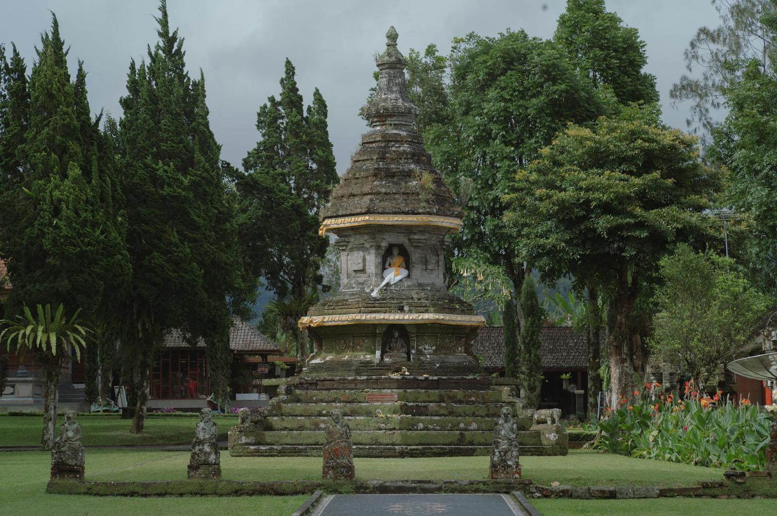 A serene ancient Balinese temple with a prominent Buddha statue in a lush garden setting