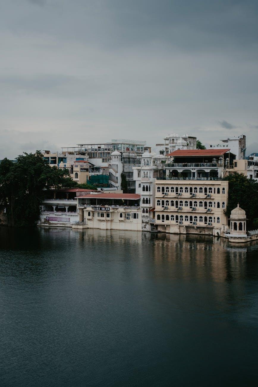 Whitewashed lakeside building reflected in still water under grey clouds