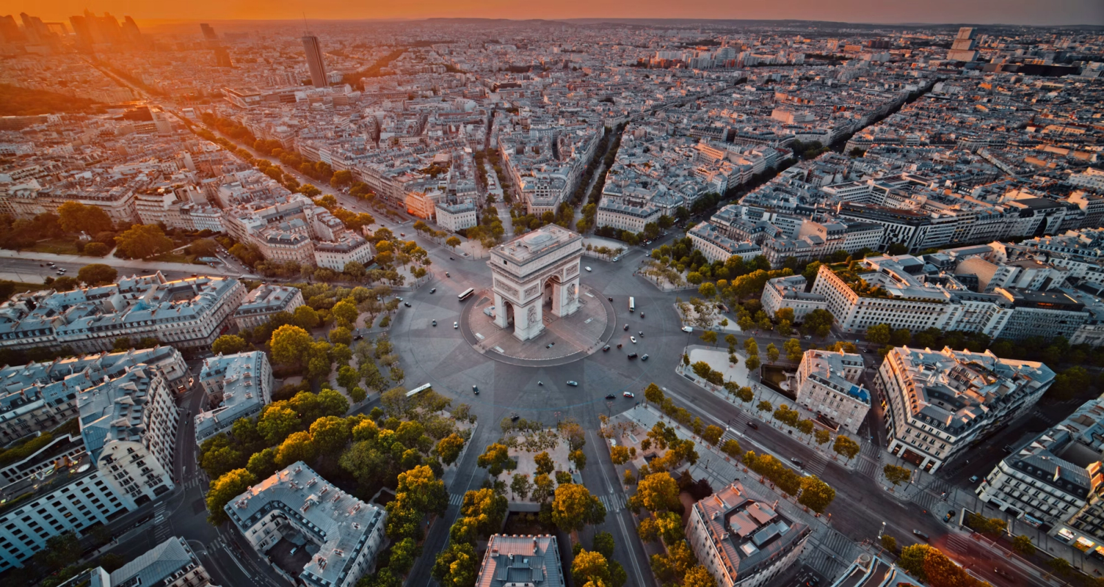 Aerial view of a monumental arch at the centre of a radiating city roundabout at sunset