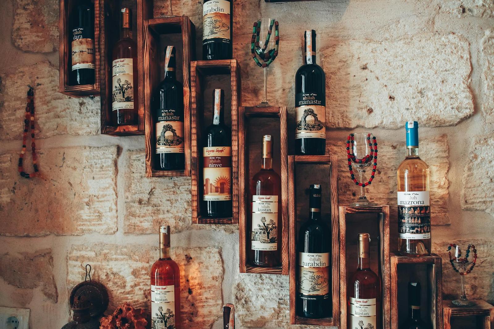 Wine bottles displayed in wooden wall boxes against old stone