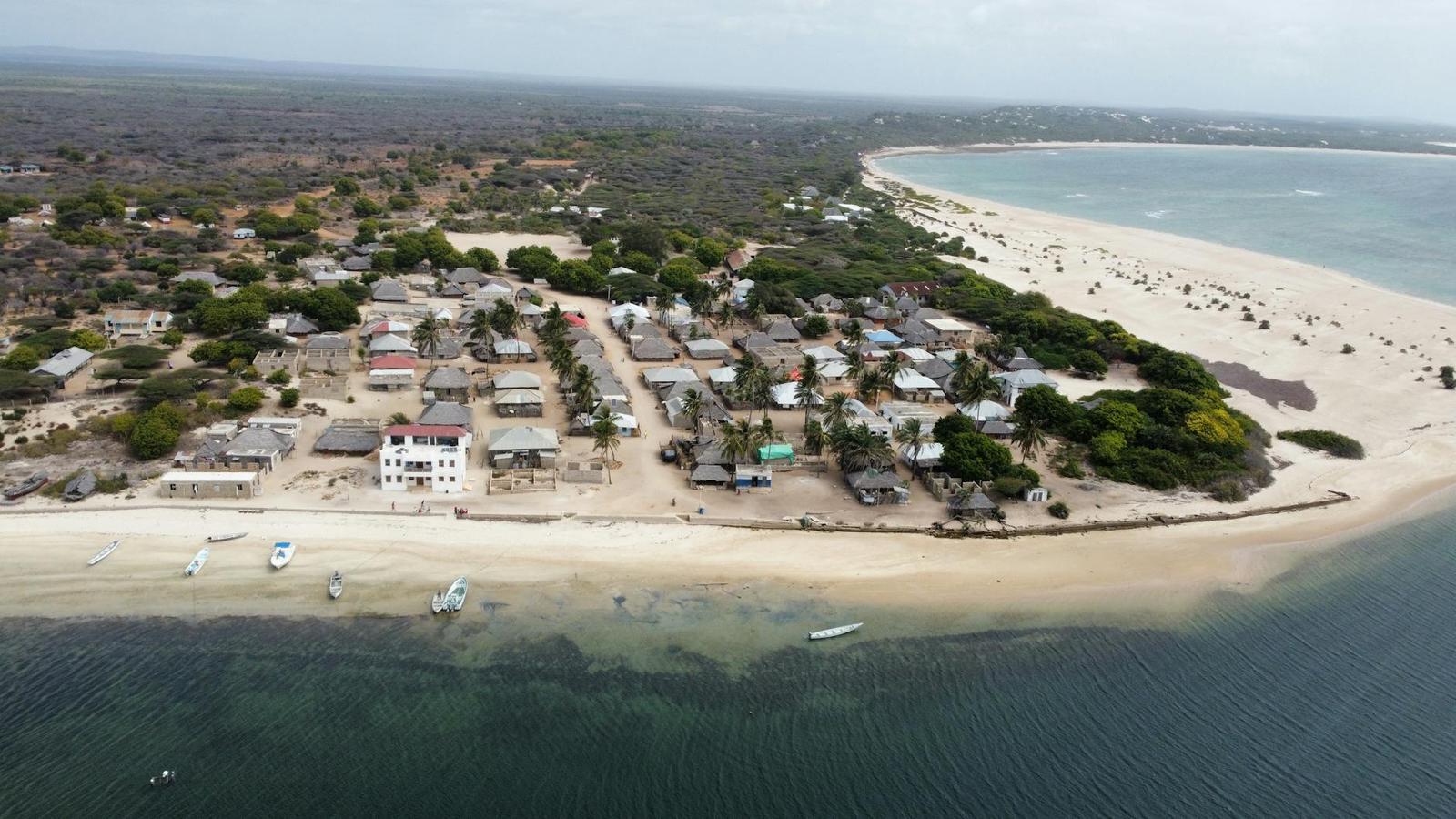 An aerial view of a beachside village between palm trees and turquoise water