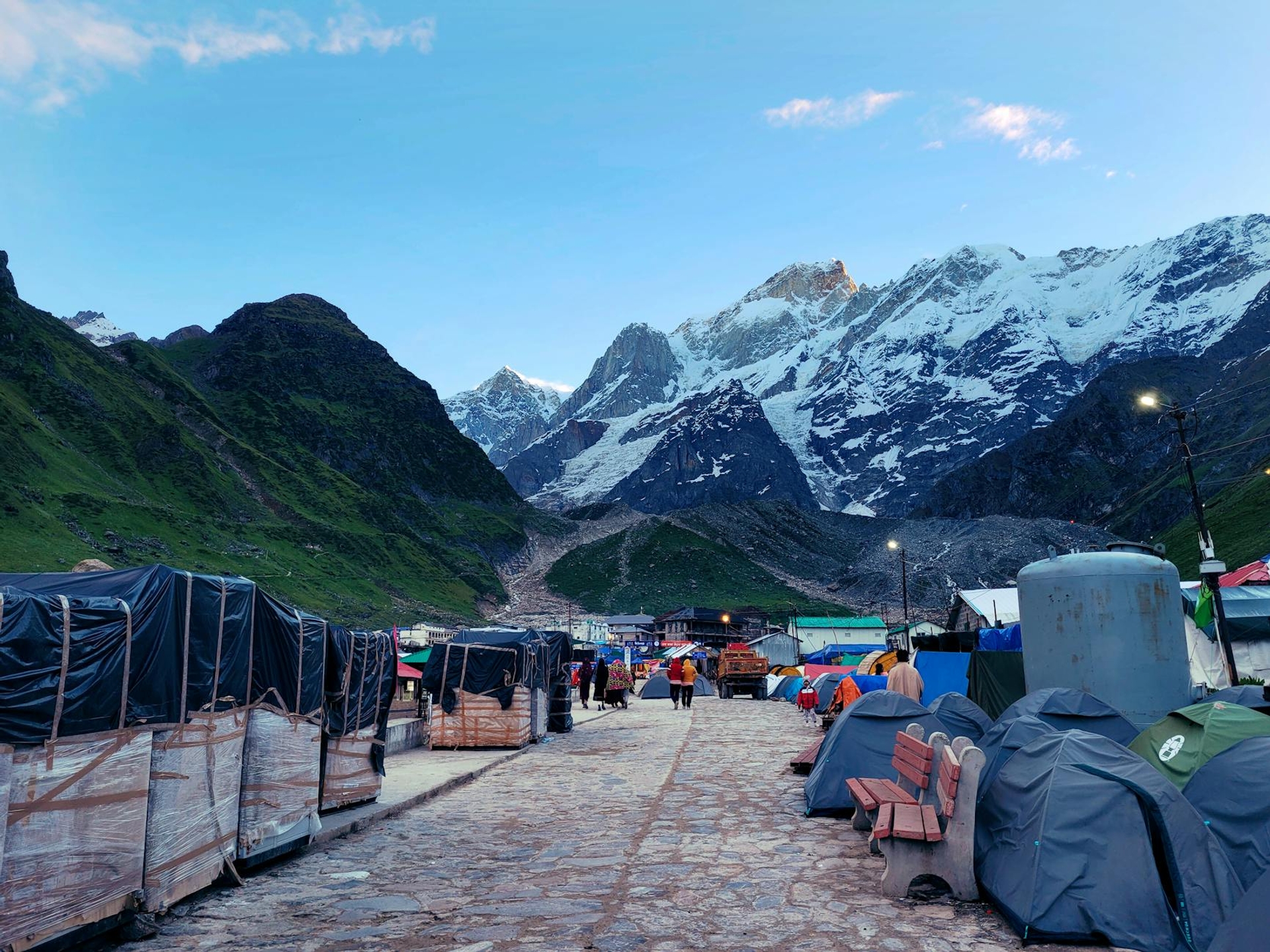 A stone path lined with tents leading toward snow capped peaks