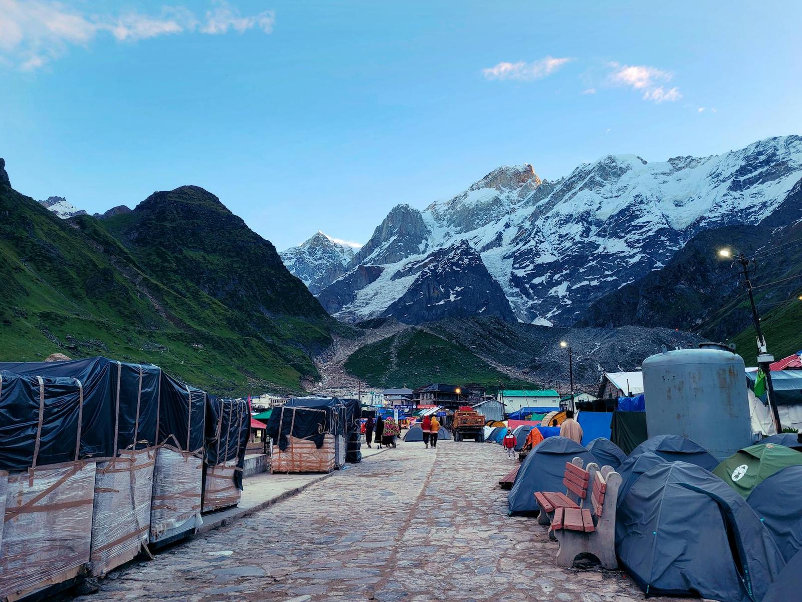 A stone path lined with tents leading toward snow capped peaks