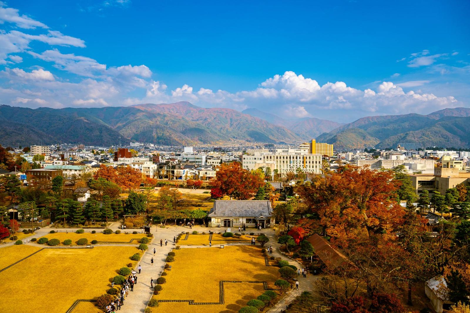 Traditional wooden building amid golden autumn foliage with mountains behind