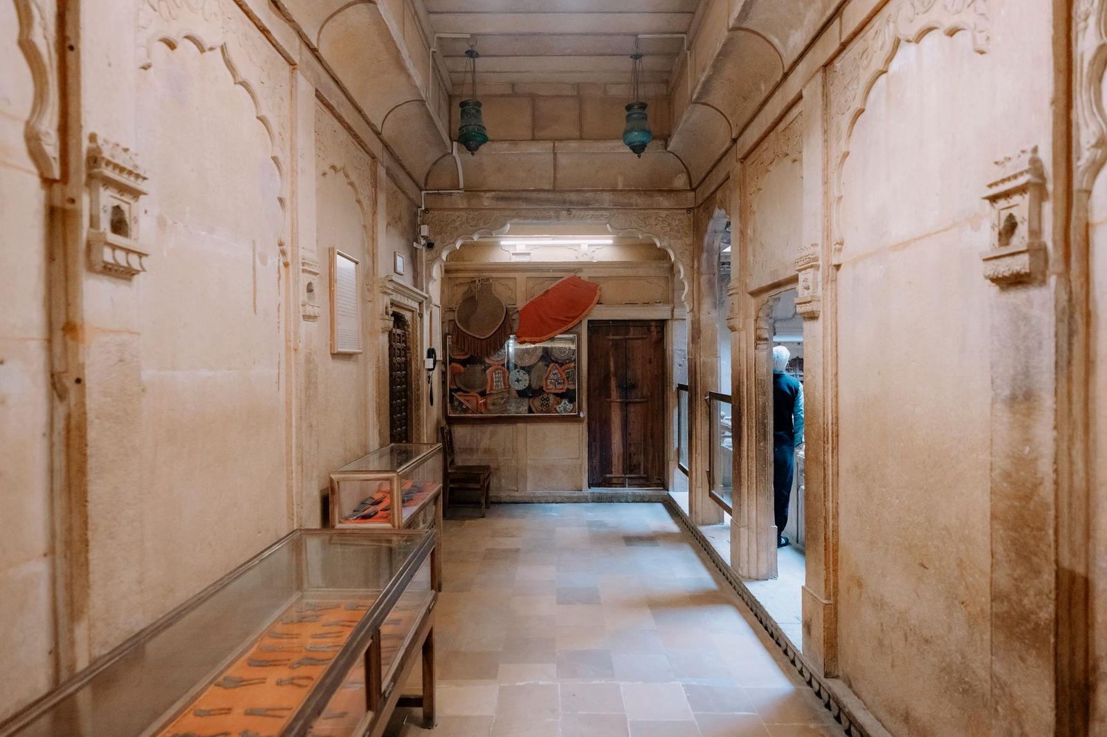 A carved sandstone hallway inside a heritage haveli with hanging lanterns