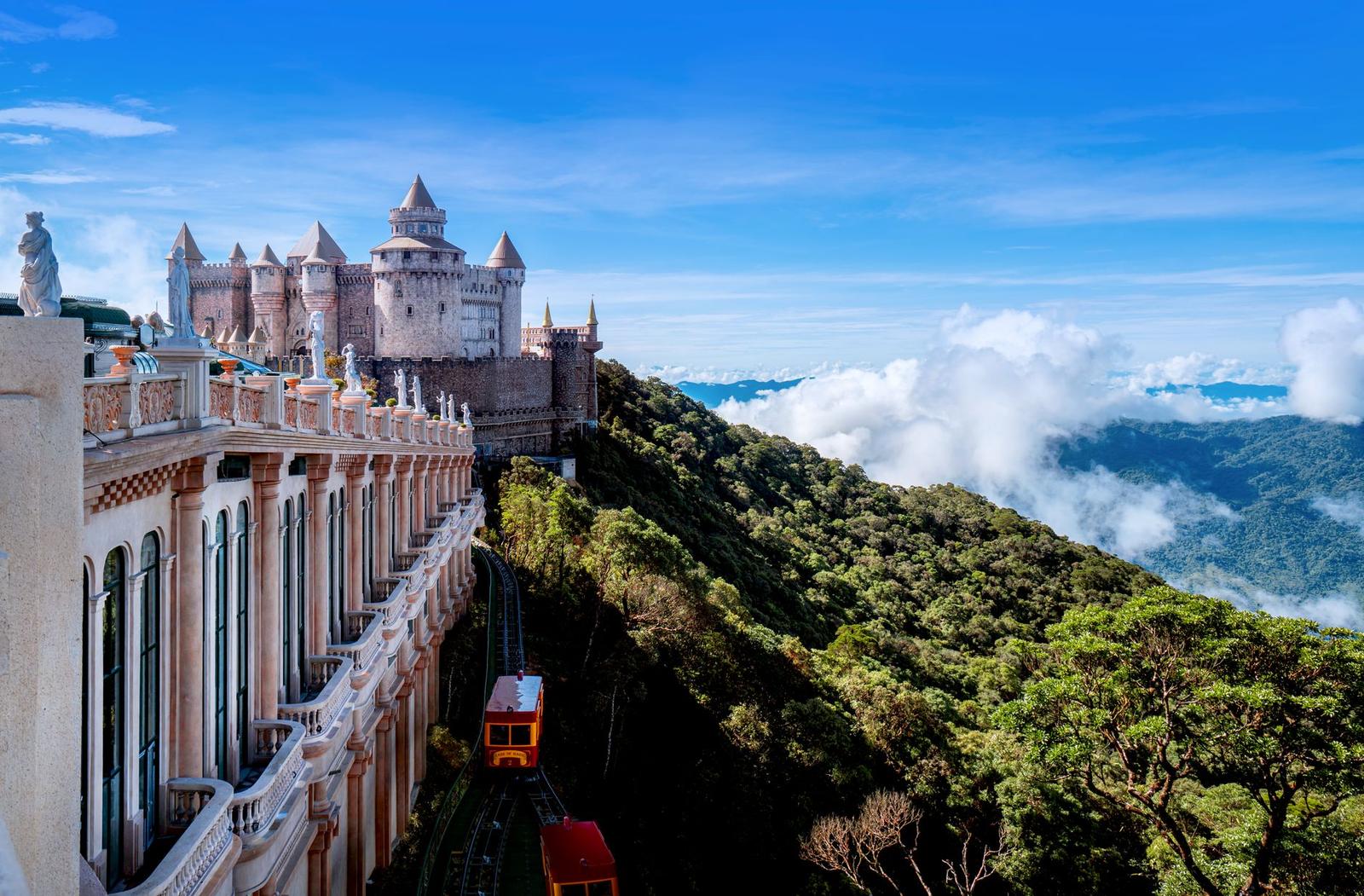 A castle-like hilltop station beside a golden bridge above a sea of clouds