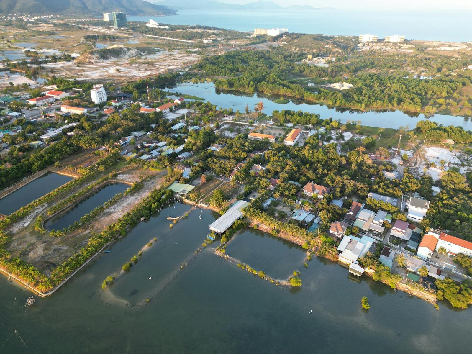 Aerial view of a riverside town with fish ponds and scattered houses near the coast